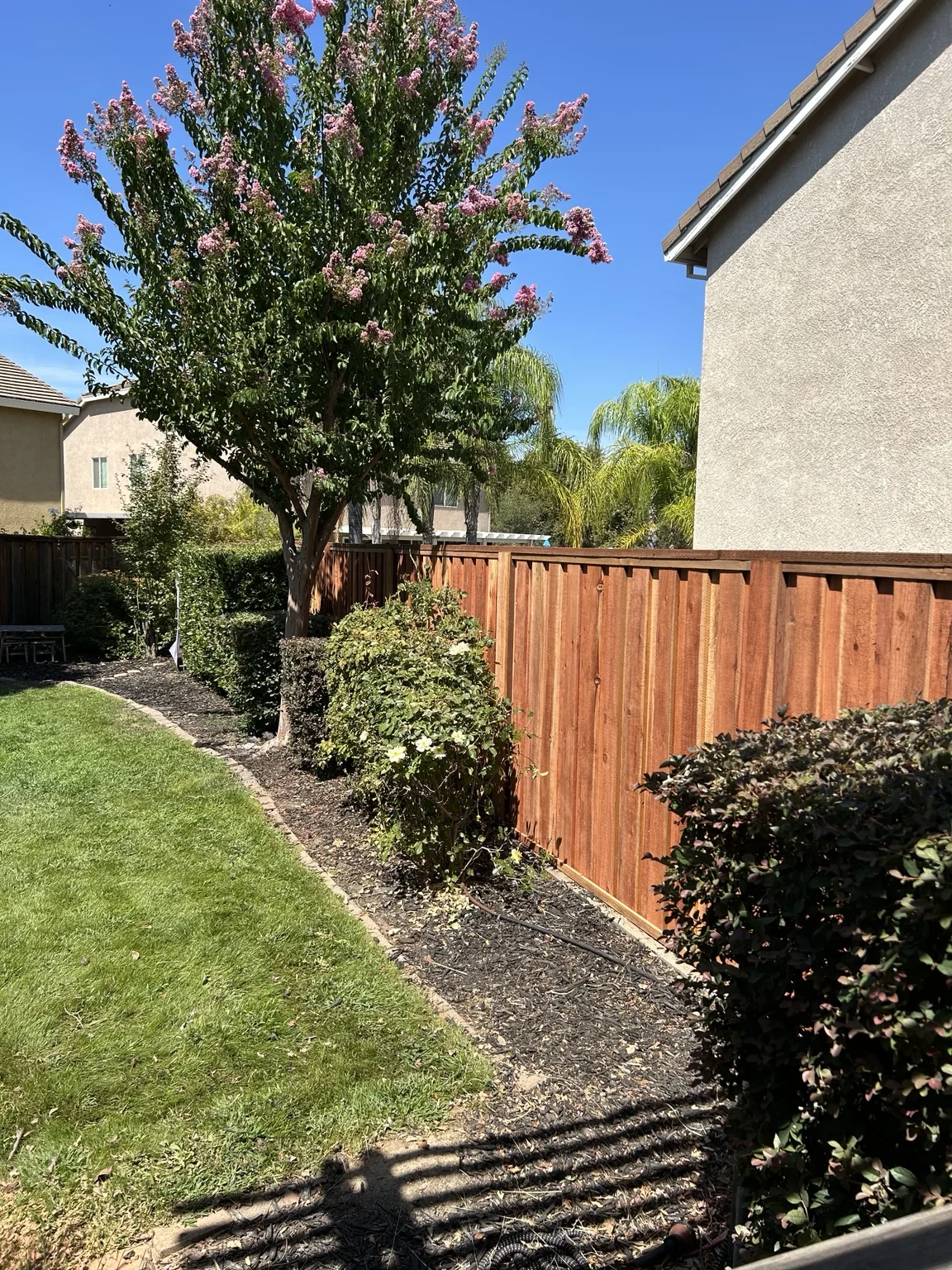 Close view of a stained wood fence beside landscaping